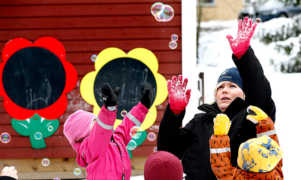 Flera barn leker med såpbubblor i snön