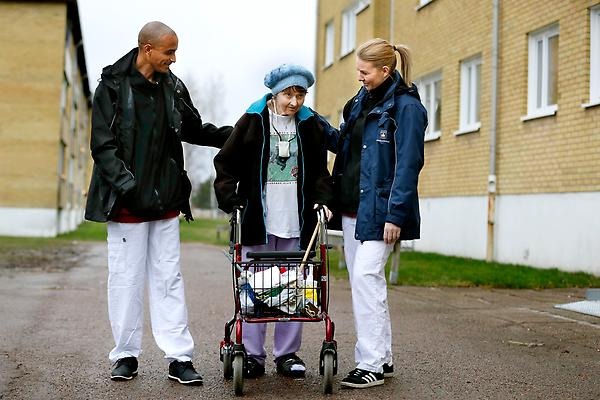 Hemtjänstpersonal på promenad med äldre dam